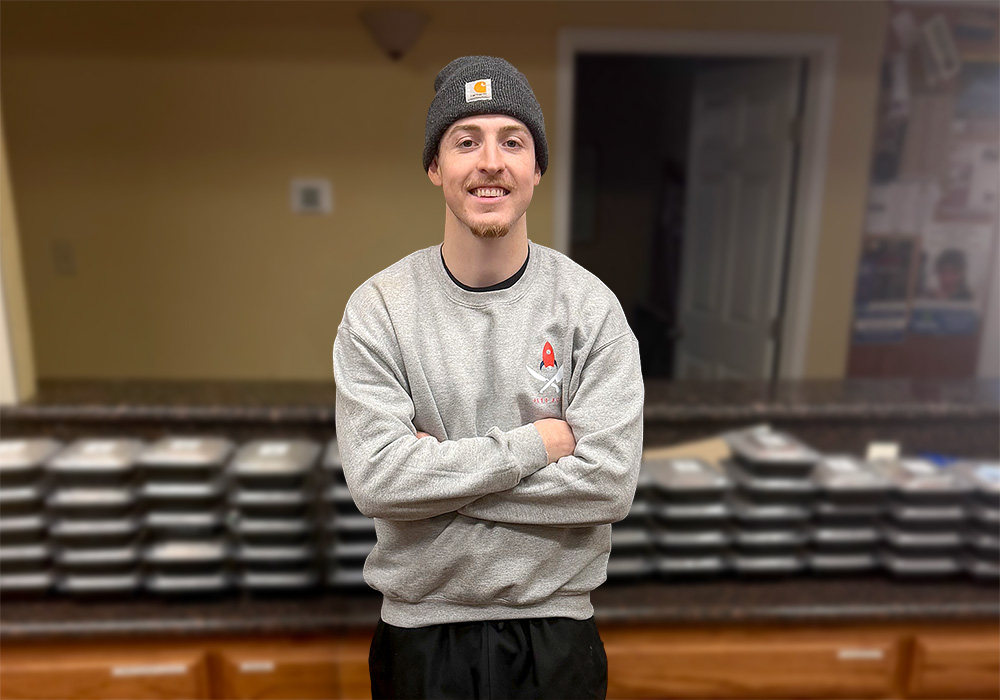 Portrait of Jett Sternberger, the chef in front of a weeks batch of prepared meals.